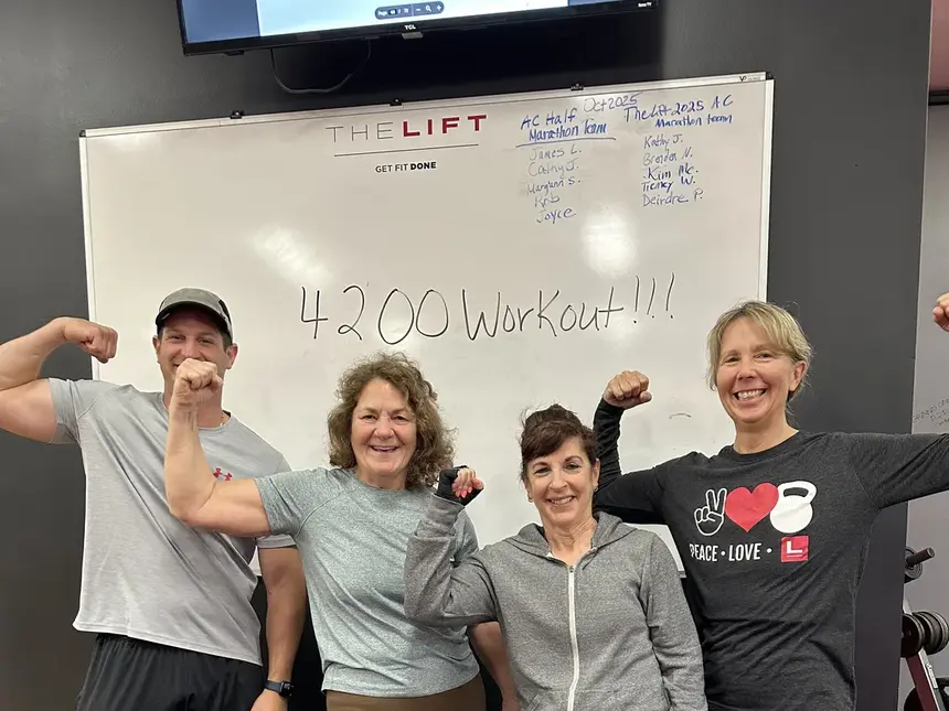 Four members flexing in front of the gym whiteboard, which reads 4200 Workout