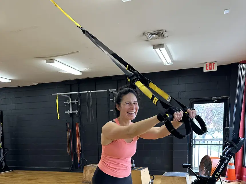 A member laughing mid-rep on the suspension trainer