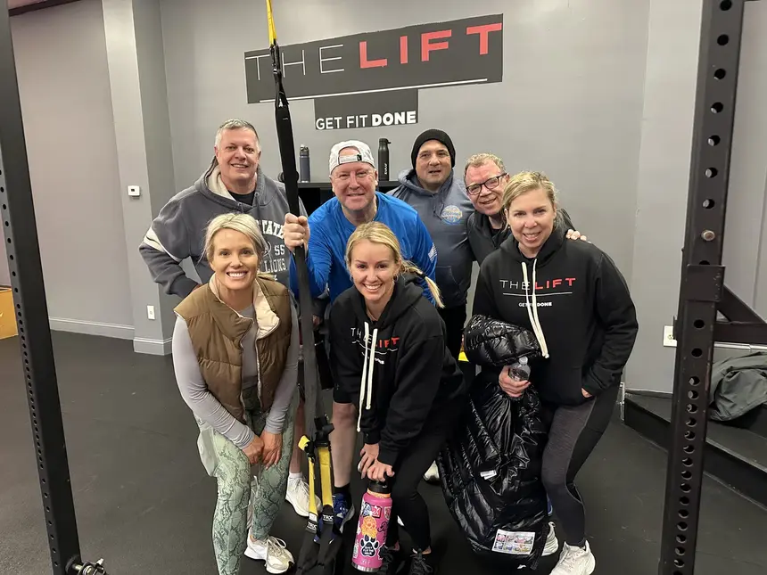 Eight members flexing together under The Lift sign
